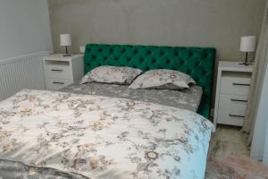 a bedroom with a bed with a green headboard and pillows at Cozy Apartment in Floreşti