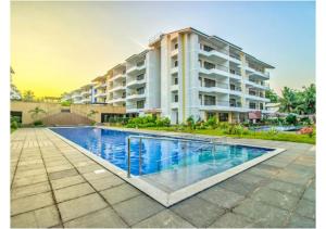 a building with a swimming pool in front of a building at Telferk Acron Seawinds Apartment- Baga in Calangute