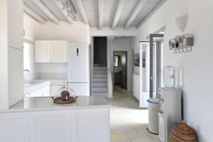 a white kitchen with white cabinets and a refrigerator at SUNRAY Paros Beach front 2 bedroom house next to kite sports in Kampos Paros