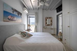 a bedroom with a white bed and a window at SUNRAY Paros Beach front 2 bedroom house next to kite sports in Kampos Paros +42 photos