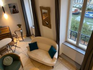sala de estar con silla y ventana en Dupleix au Fil du Canal, en Narbona
