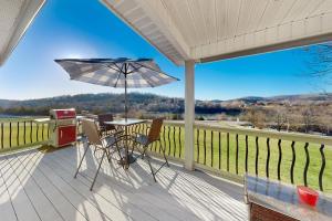 a porch with a table and an umbrella and a grill at Hideaway Harbor in Holiday Island