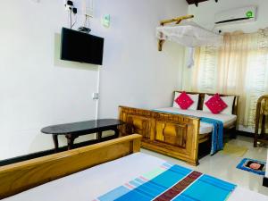 a room with a bed and a table and a tv at Rich Resort & Restaurant in Anuradhapura