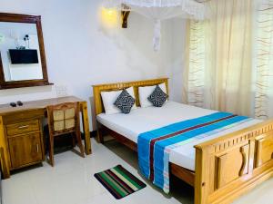 a bedroom with a bed and a desk and a mirror at Rich Resort & Restaurant in Anuradhapura