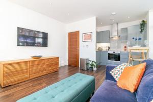 sala de estar con sofá azul y cocina en *20% off Monthly* St Albans City Centre Apartment en Saint Albans