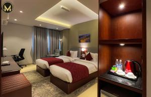 Muscat Express Hotel في مسقط: غرفة فندقية بسريرين ومكتب