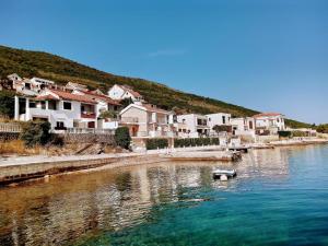 a small boat in the water in front of houses at Apartments Obradovic in Krasici