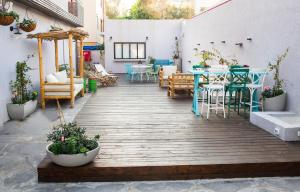 une terrasse en bois avec des tables et des chaises. dans l'établissement Domus Bat Galim Hotel, à Haïfa