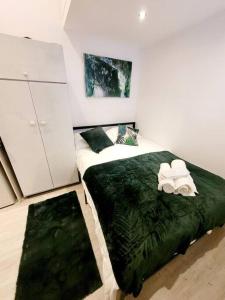ein Schlafzimmer mit einem Bett mit einer grünen Decke in der Unterkunft (S7) Great Studio Next To A Tube Station! in Harrow on the Hill