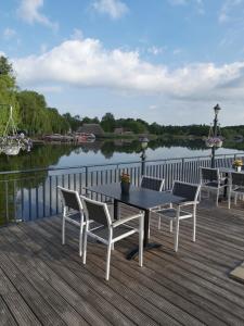 einen Tisch und Stühle auf einer Terrasse neben einem See in der Unterkunft Seehotel Krakow am See in Krakow am See