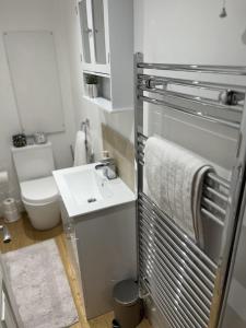 a white bathroom with a sink and a toilet at Gorgeous 2 floor 3 bed Apartment in St. Leonards