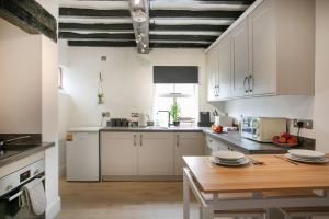 a kitchen with white cabinets and a wooden table at Central 4 Bedroom House in Derby