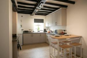a kitchen with white cabinets and a wooden island with stools at Central 4 Bedroom House in Derby