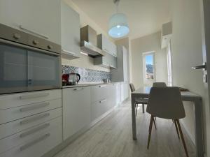 a kitchen with white cabinets and a table with a chair at Address Home I Colori Del Mare in Ospedaletti