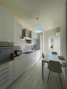 a kitchen with white cabinets and a table with chairs at Address Home I Colori Del Mare in Ospedaletti