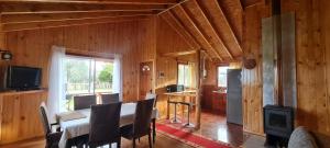 a dining room with a table and a kitchen at Cabañas Susurros del Bosque in Ancud