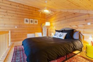 1 dormitorio con 1 cama en una pared de madera en Le chalet des bois, en Lalaye
