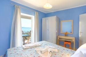 niebieska sypialnia z łóżkiem i oknem w obiekcie Alexandra Apartment w Nisaki