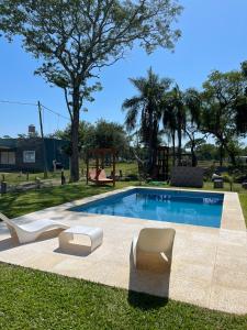 a swimming pool with two chairs and a playground at Bitcoin's House II. Laguna Brava in Corrientes