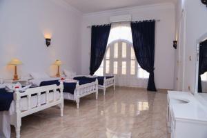 a bedroom with four beds and a sink and a window at Luxor Oasis Guest House in Luxor