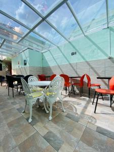 um grupo de mesas e cadeiras num quarto com tectos de vidro em Rota BH Hostel em Belo Horizonte