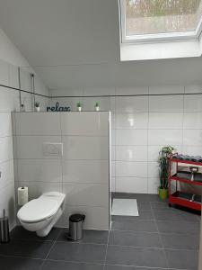 a white bathroom with a toilet and a window at Penthouse perfekt für Teams, Familien und Gruppen in Bad Mergentheim