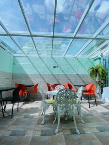 - un ensemble de tables et de chaises dans une pièce dotée de plafonds en verre dans l'établissement Rota BH Hostel, à Belo Horizonte