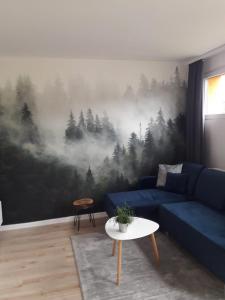 a living room with a blue couch and a forest mural at Apartament Bora Stronie Śląskie in Stronie Śląskie