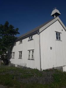 Un fienile bianco con una torre sopra. di Lofoten - Stor leilighet i idyllisk fiskevær a Sund