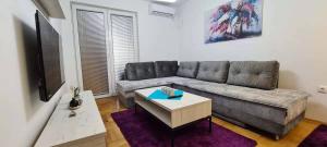 ein Wohnzimmer mit einem Sofa und einem Tisch in der Unterkunft Stylish Violet & Modern Apartment in Skopje