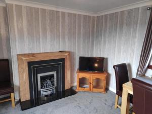 a living room with a fireplace and a tv at Lovely 2BD Flat in picturesque Limekilns Fife in Limekilns