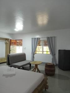 a room with a bed and a couch and a table at Skott's Comfy Lodge in Bantayan Island