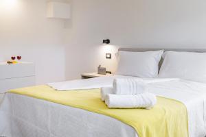 una camera da letto con un letto bianco e asciugamani di Bandiera 68 Apartment a Cagliari