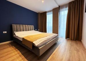 Cubrio Apartments في ياش: غرفة نوم بسرير بجدران زرقاء وارضيات خشبية