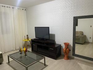 Apartamento Diamante في ديامانتينا: غرفة معيشة مع تلفزيون ومرآة
