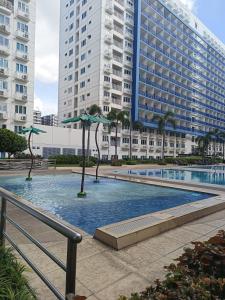 - une piscine avec des parasols en face d'un bâtiment dans l'établissement Amigo's Place at Sea Residences, à Manille