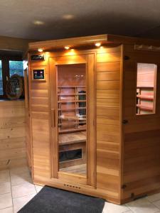 a wooden cabinet with a glass door in a room at Le joli bois 12 personnes 5/ch spa/sauna Gérardmer in Gérardmer