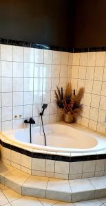 uma banheira num quarto em azulejo com uma planta em Vogtlandperle em Oelsnitz/Vogtland