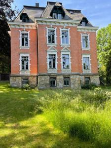 a large brick building with white windows on a grass field at Vogtlandperle in Oelsnitz/Vogtland