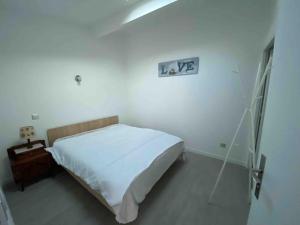 - une chambre blanche avec un lit et une horloge murale dans l'établissement La maison de la pointe rouge, à Marseille