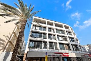 un edificio blanco alto con una palmera delante de él en Lovely studio on Frishman beach w Bomb Shelter M1, en Tel Aviv