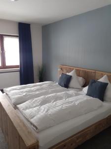 1 cama grande con sábanas blancas y almohadas azules en Pension Orketal, en Medebach