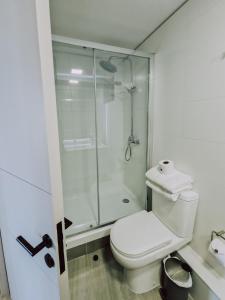 a white bathroom with a shower and a toilet at Departamento en Costas de Montemar, a pasos de la playa, con Vista al Mar, Piscina y GYM in Valparaíso