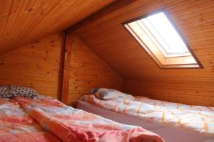 a room with two beds in a attic with a window at Cabana Perla Transilvaniei in Cluj-Napoca