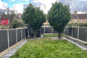 Seven Kings的住宿－Home in Ilford，两棵树在院子里,有栅栏