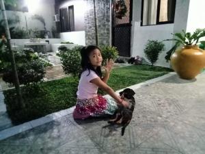 a little girl sitting on the ground with a dog at Natalie's Villa in Iloilo City