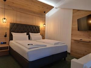 a bedroom with a large bed and a flat screen tv at Riessersee Hotel in Garmisch-Partenkirchen