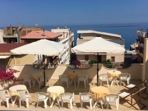 a group of chairs and tables and umbrellas on a building at Hotel Sylesia in Letojanni