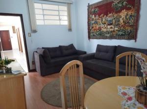 ein Wohnzimmer mit einem Sofa und einem Tisch in der Unterkunft Apartamento Central, quarto andar in Serra Negra