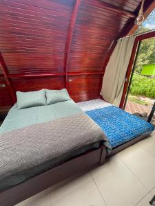 Cama en habitación pequeña con ventana en Glamping Campo Alegre, en Cartago